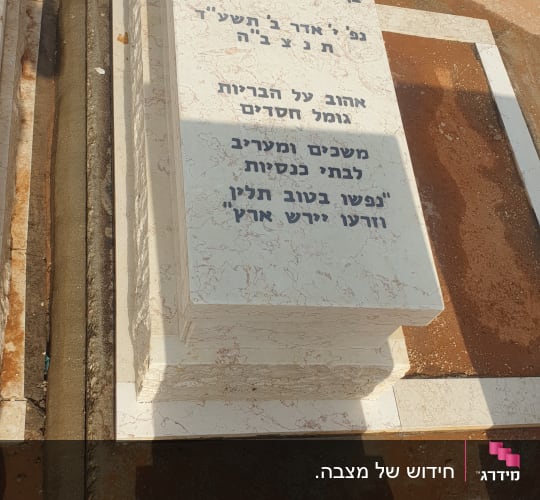 מצבת שיש ואבן עם כיתוב חרות בשחור בבית עלמין